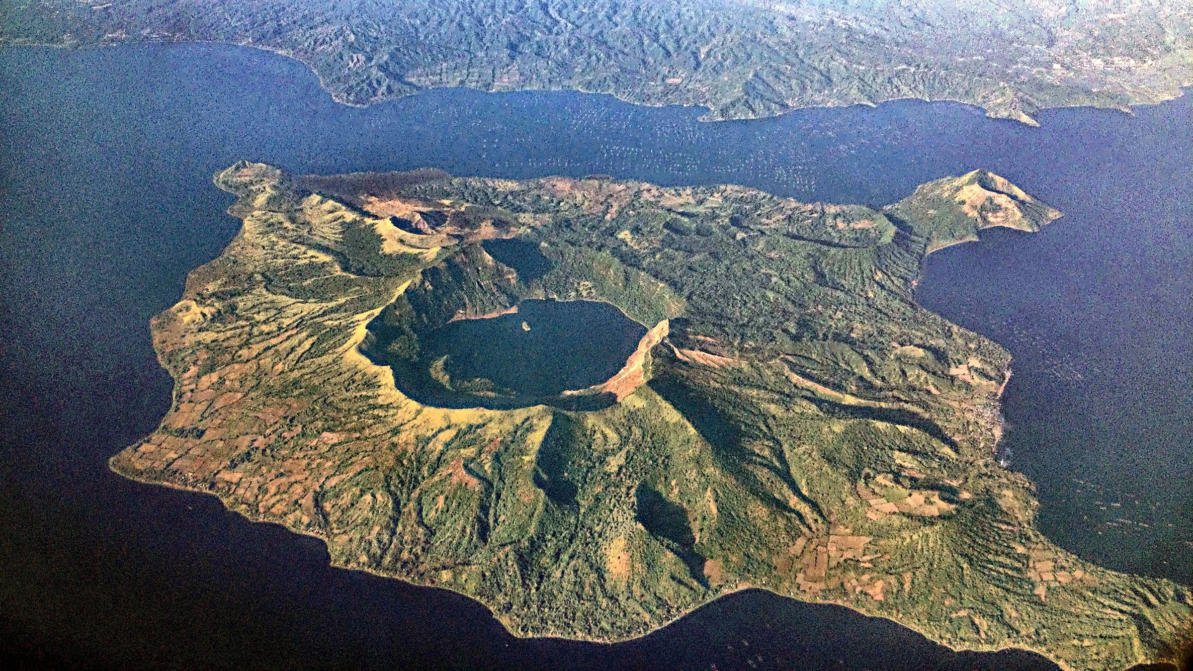 Aerial photograph of Volcano Island in Lake Taal, Philippines, with Main Crater Lake at its centre and the small island of Vulcan Point inside the crater lake